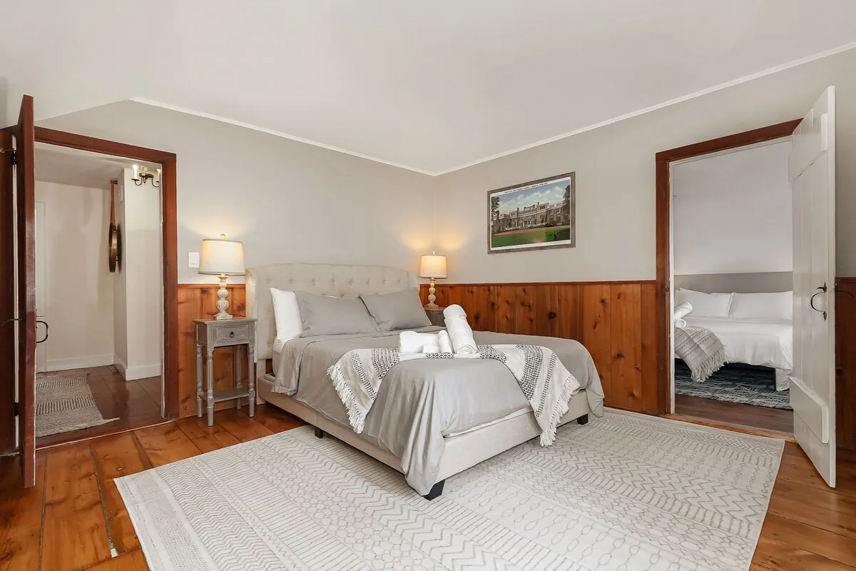 Large bedroom with an upholstered bed, sitting area and hardwood floors