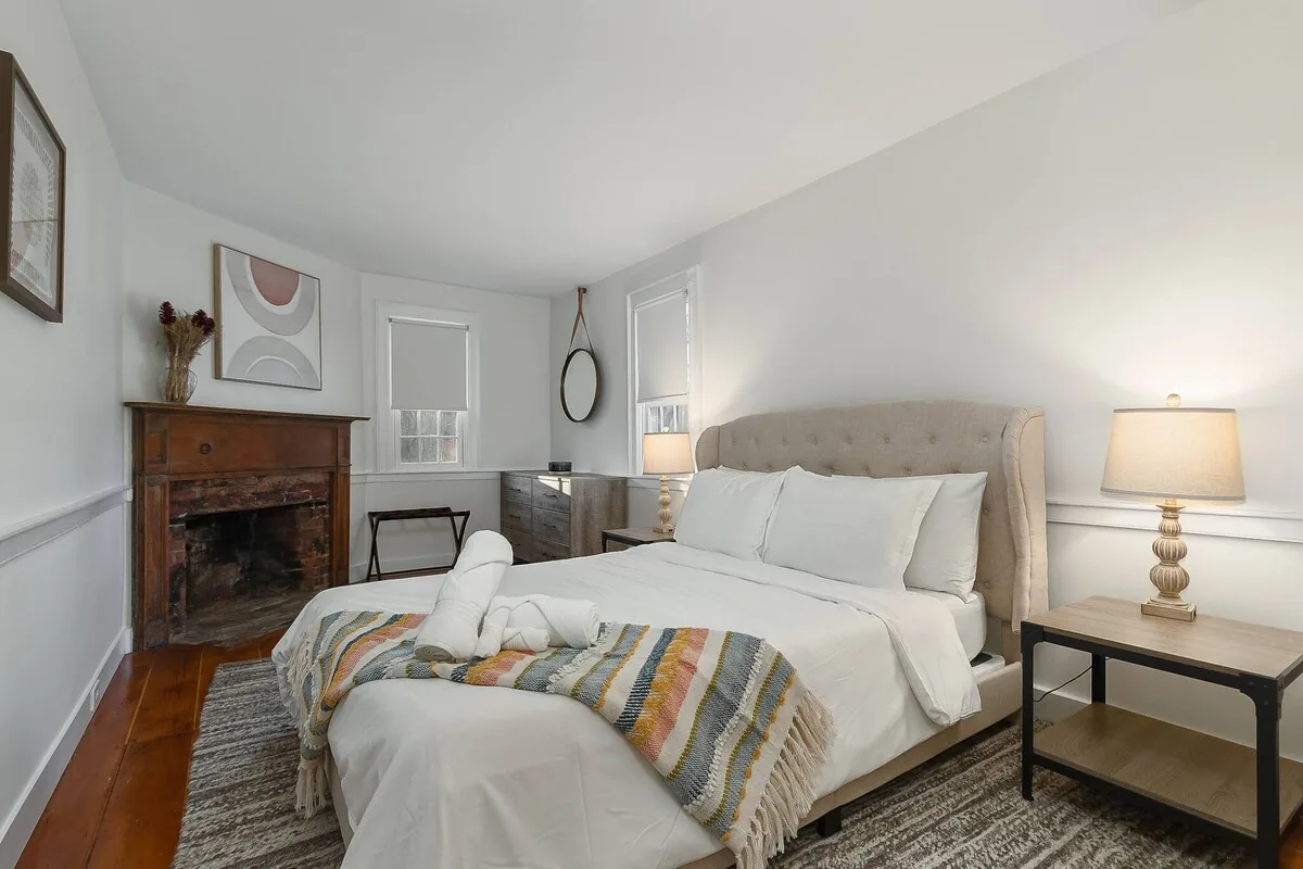 Bedroom with white bed and decorative fireplace