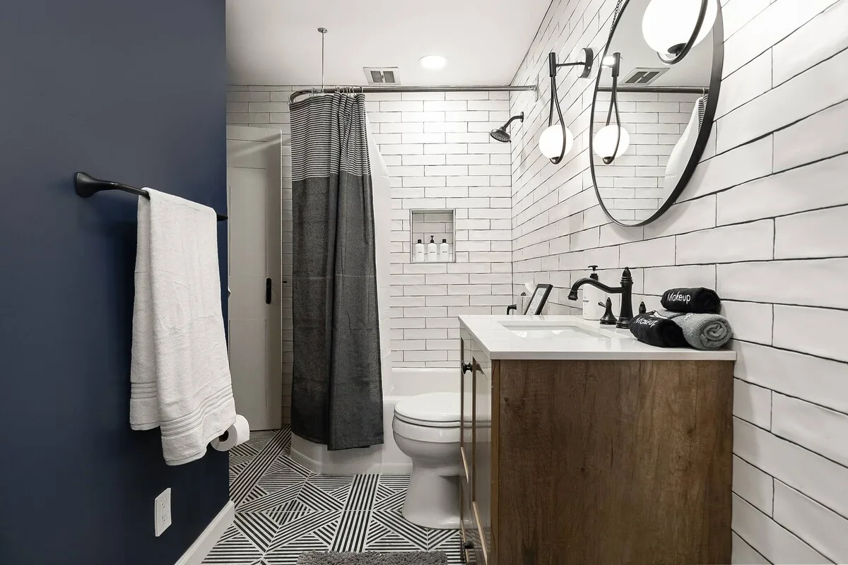 Full bathroom with white tile and dark walls