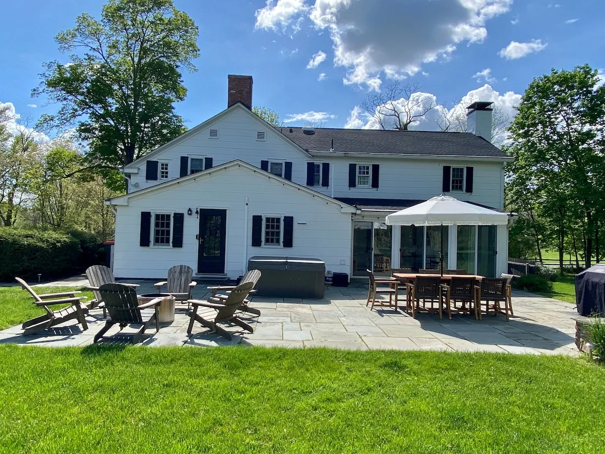 Rear of the white farmhouse opening onto a broad lawn
