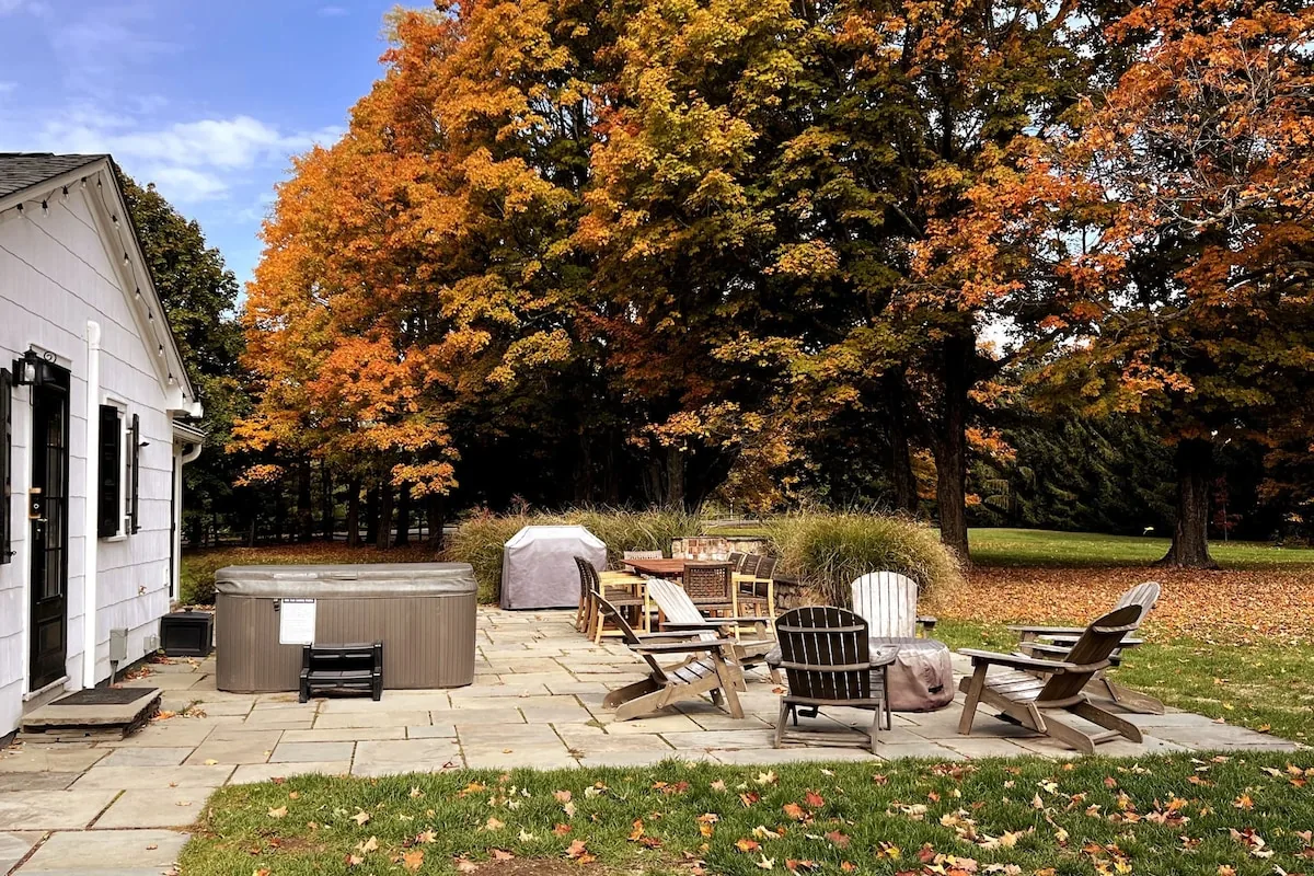 Farmhouse patio framed by vivid orange and gold autumn foliage
