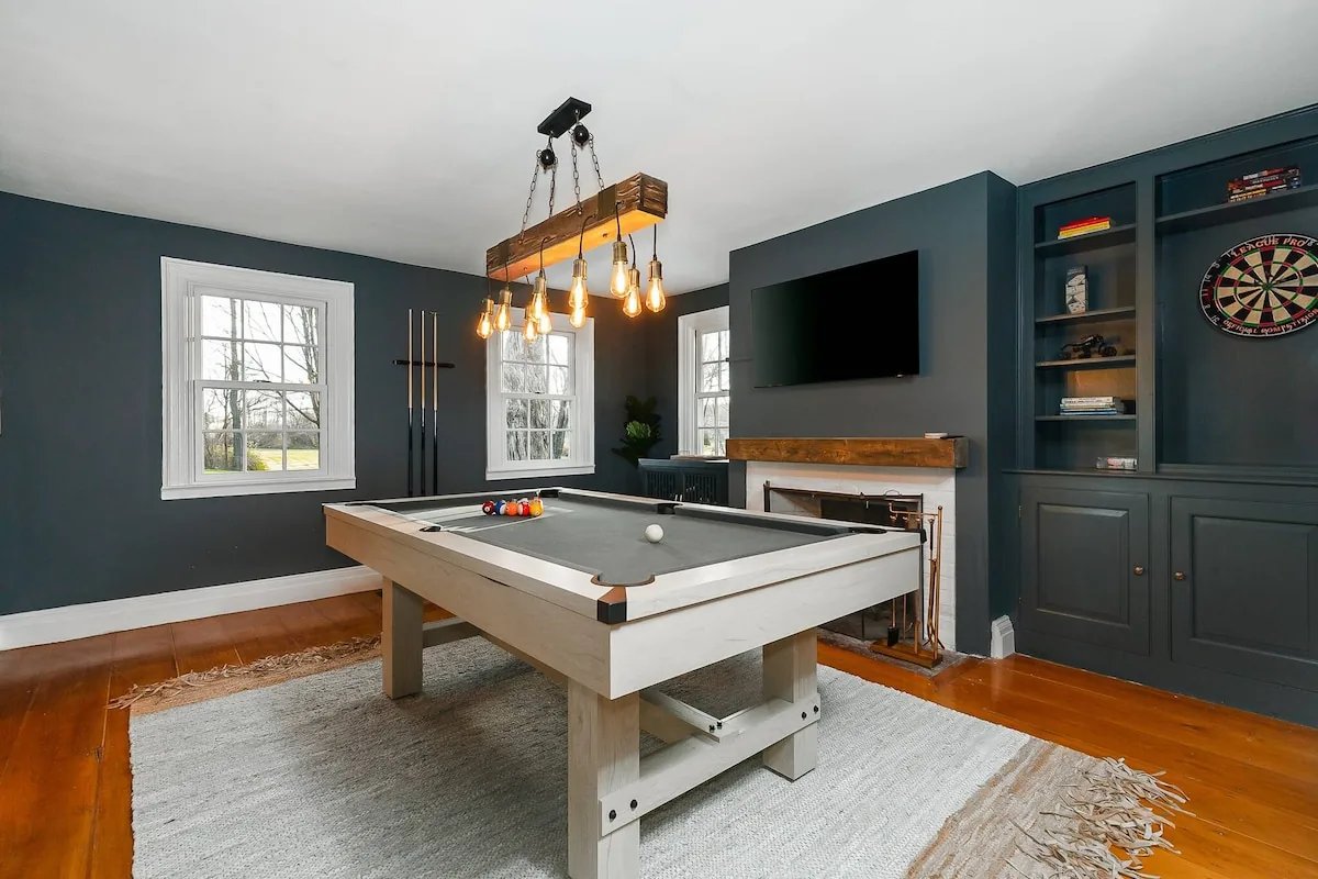 Pool table in a deep green game room with darts and a television